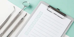 Dental check up cost on a clipboard checklist next to dental tools.