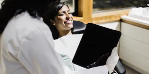 Dentist showing digital smile design on a tablet to a patient in a modern dental office