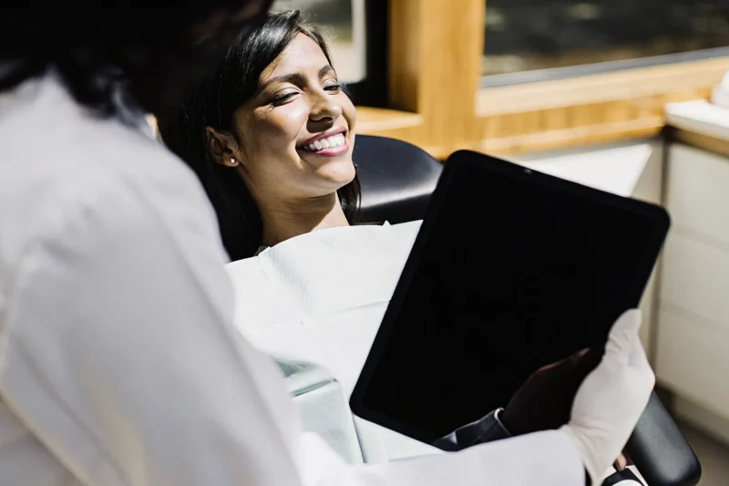 Dentist showing digital smile design on a tablet to a patient in a modern dental office