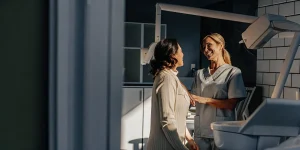 A modern dental office in soft natural light where a friendly dentist reviews a patient's healthy smile