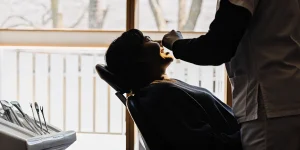 A relaxed adult patient reclining comfortably in a bright, modern dental office while a friendly dentist explains the procedure