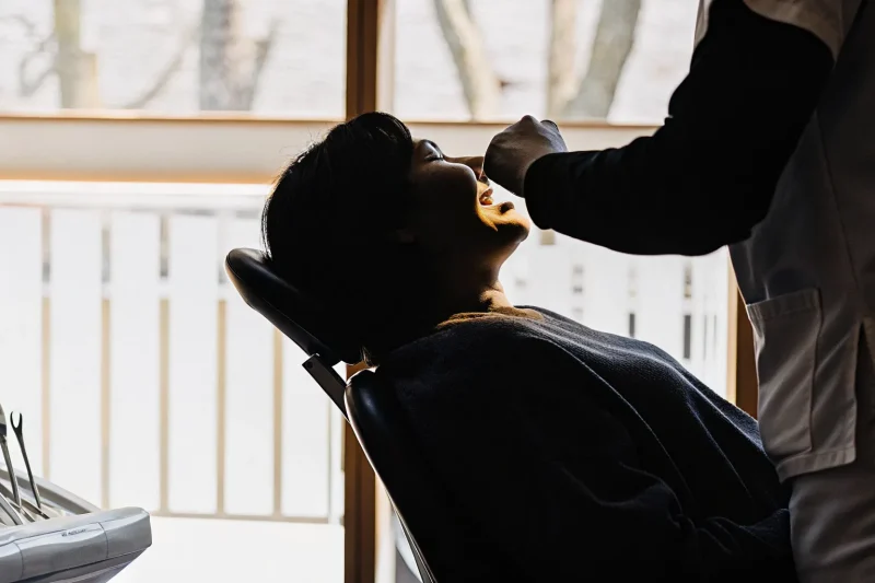 A relaxed adult patient reclining comfortably in a bright, modern dental office while a friendly dentist explains the procedure
