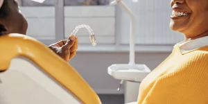 Adult patient smiling with a dentist holding a clear aligner tray in a modern dental office